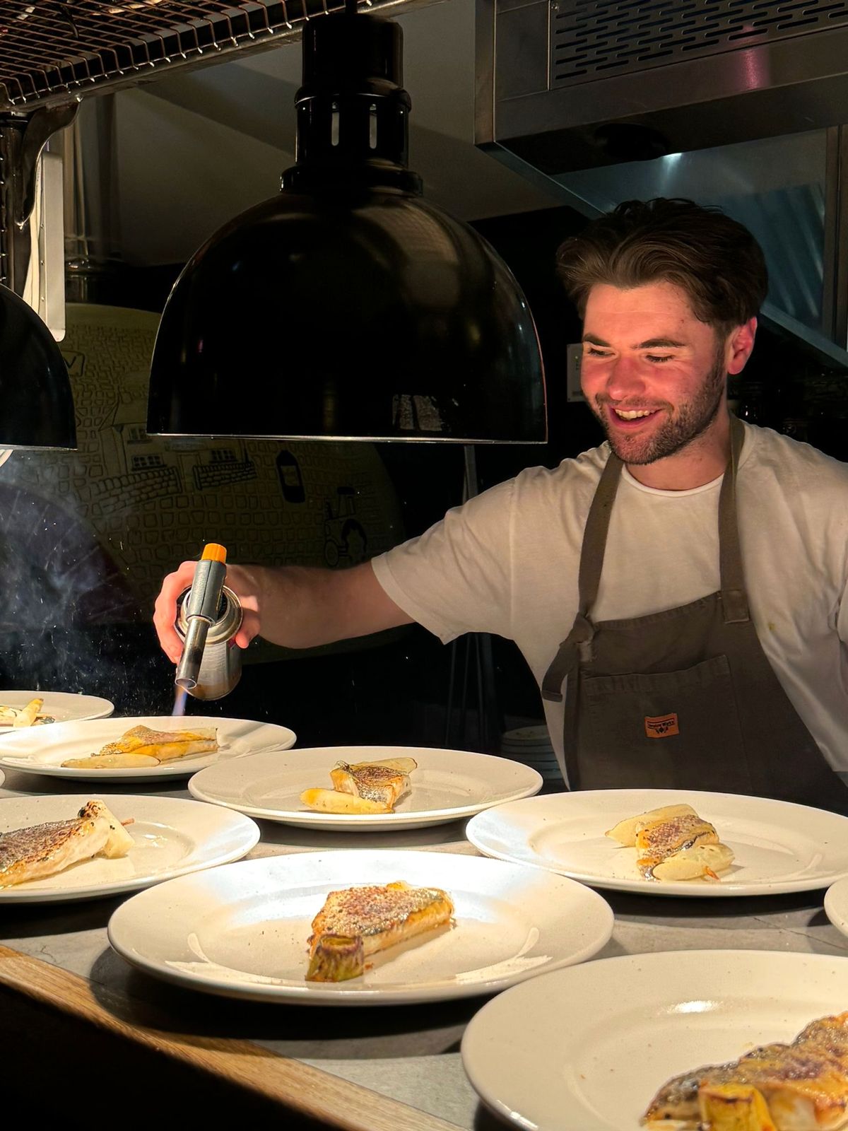 Ryan Bland finishing plates of fish with a blowtorch at the pass