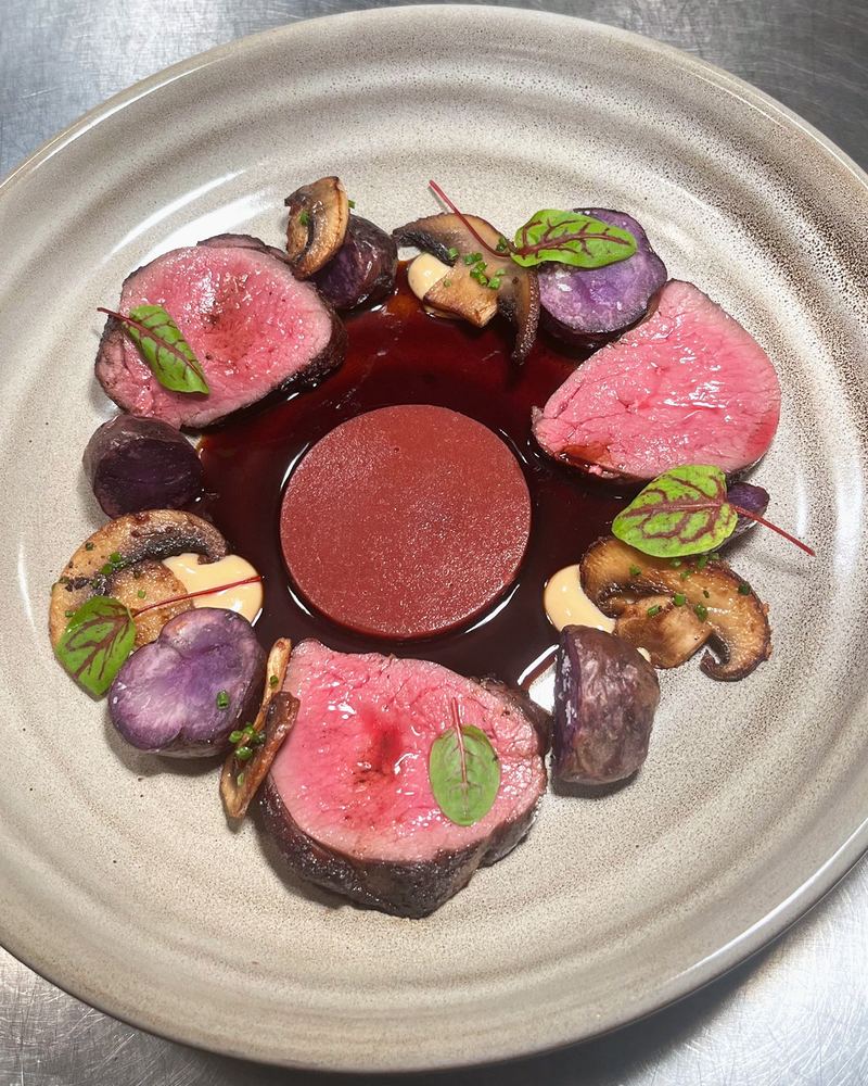 A plated beef dish with beetroot, purple potatoes, mushrooms and sorrel